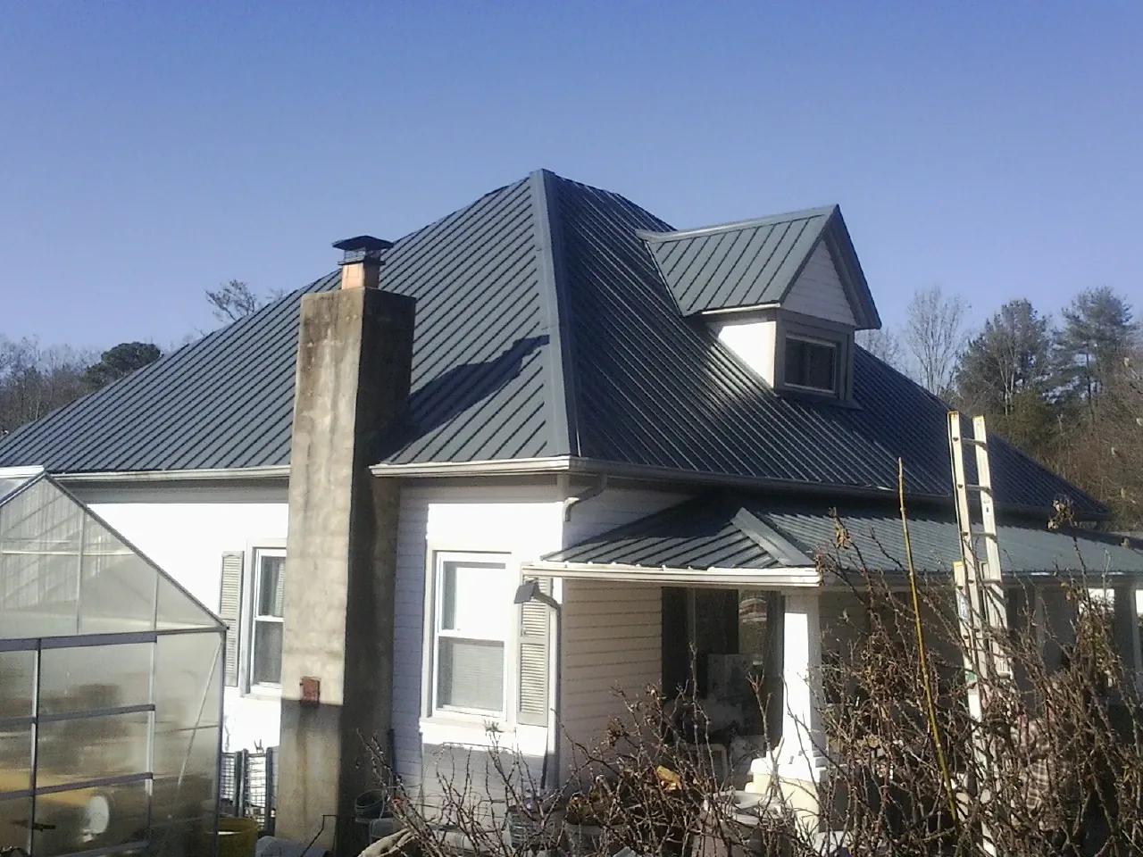 Dark blue standing seam metal roof on a white farmhouse with dormer — Slate & Tile Roof Repair by Roofing Brothers in Fort Klamath