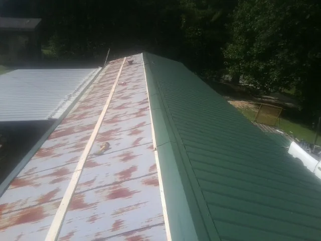 Old rusted panels beside newly installed green metal roofing — Wind Damage Roof Repair by Roofing Brothers in Fort Klamath