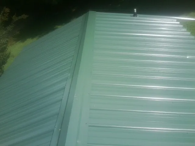 New green metal panels meeting at the ridge of a roof — Flat Roof Repair work by our crew in Fort Klamath