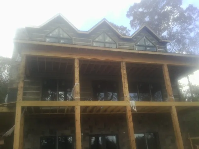 Dormers and porch framing on a large log home under construction — Roof Coating work by our crew in Fort Klamath