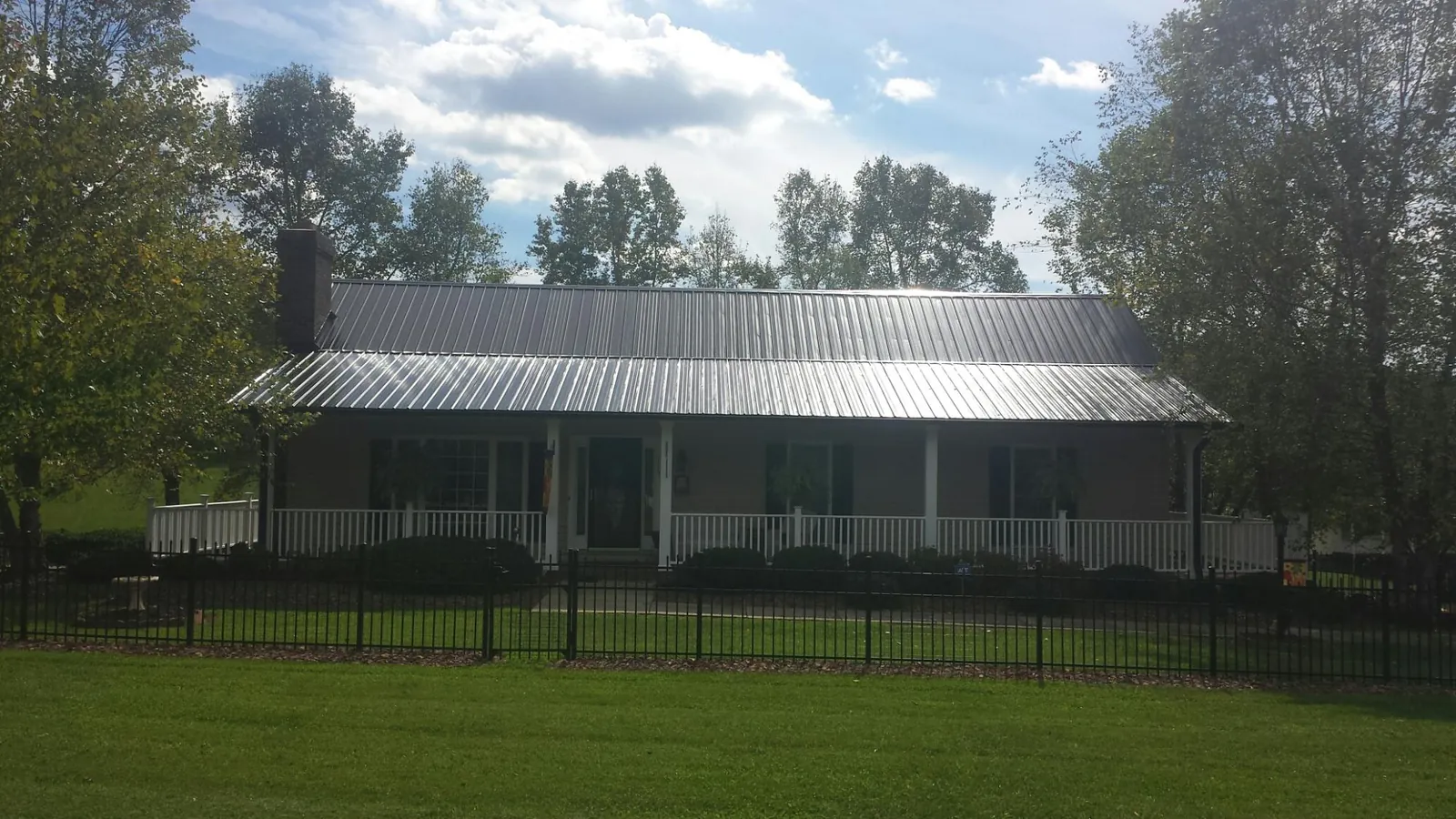 Gray metal roof on a brick ranch with a full width front porch — Gutter Guard Installation work by our crew in Fort Klamath