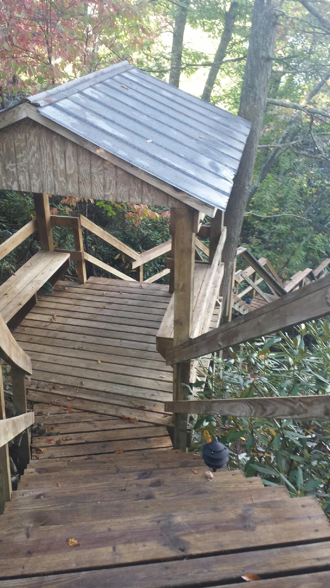 Metal roofed shelter over wooden steps on a wooded walkway — Skylight Repair & Installation work by our crew in Fort Klamath