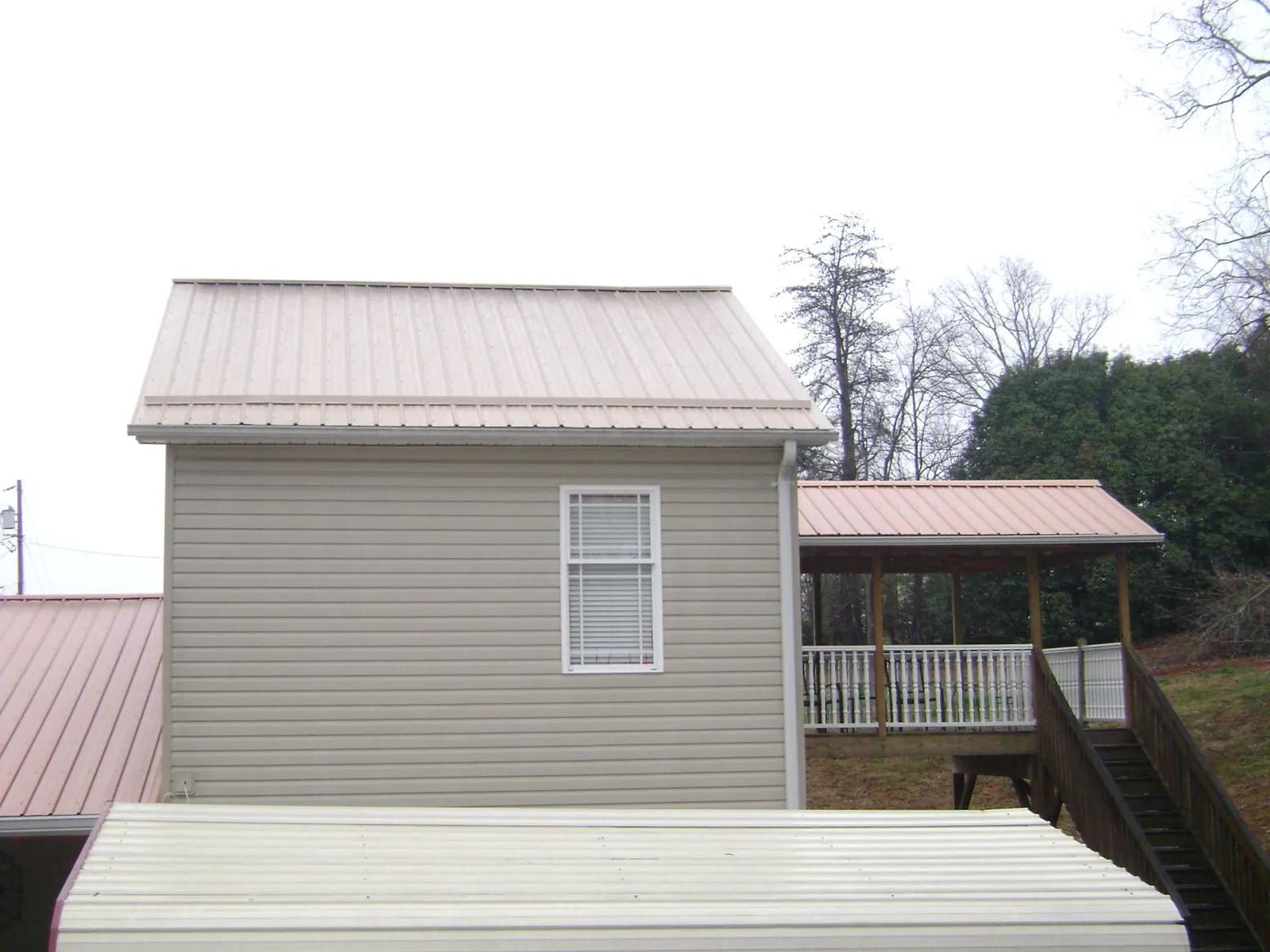 Tan metal roofs on a two story addition and attached porch, from a Roof Replacement job in Fort Klamath