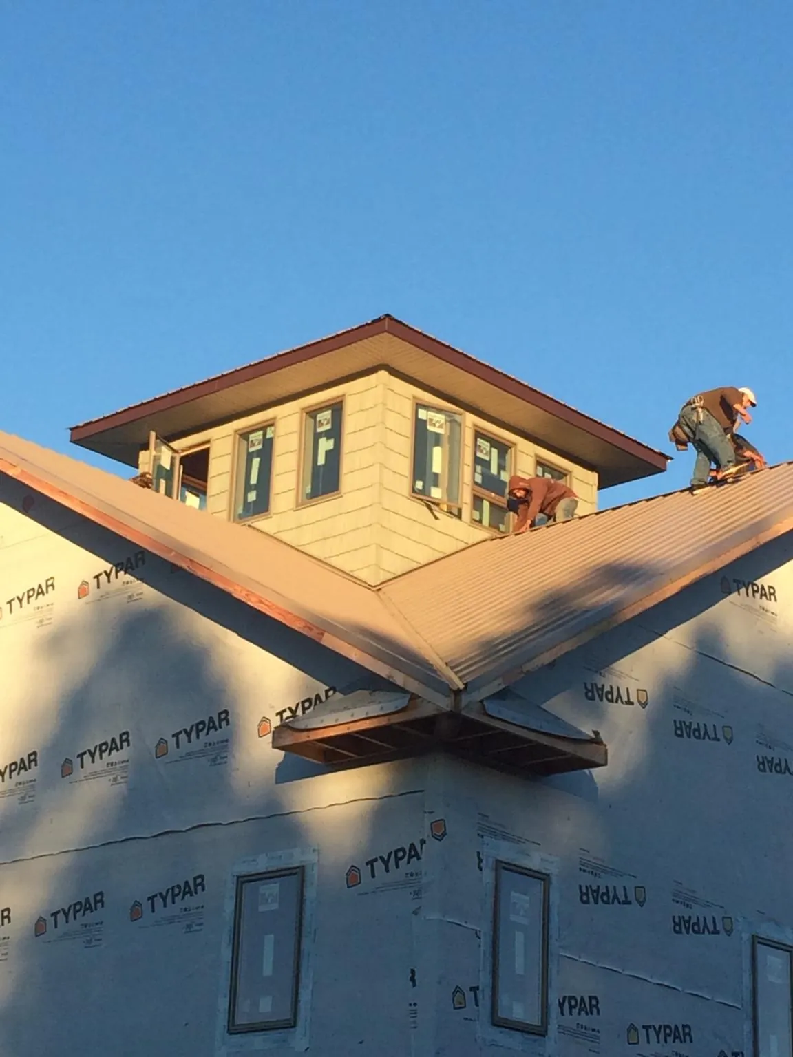 Roofers working around a rooftop cupola on a new metal roof at sunset — Roof Waterproofing in Fort Klamath by Roofing Brothers